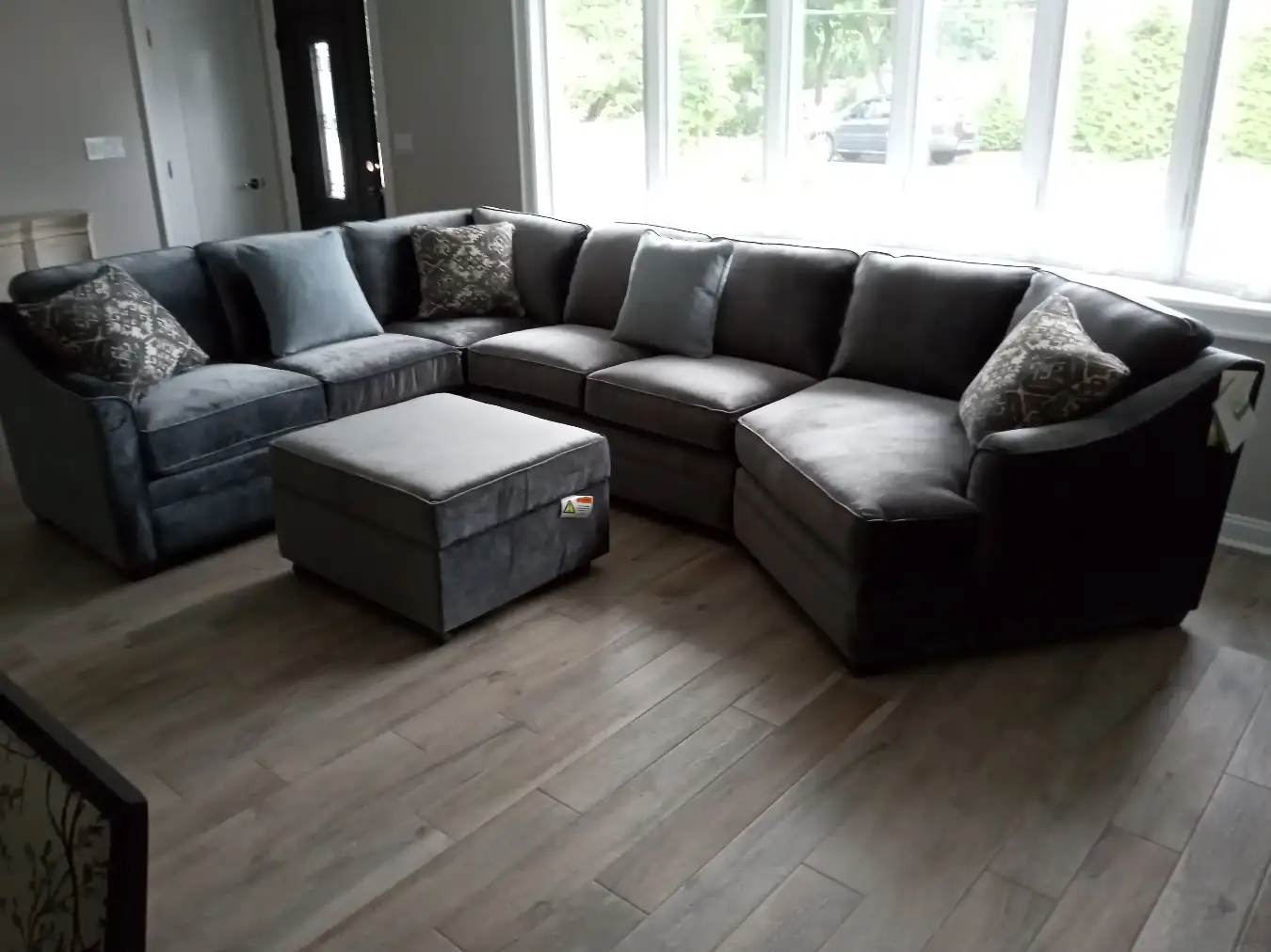 Sectional sofa and ottoman in a customer’s living room in front of a bay window, delivered and arranged by RF Delivery
