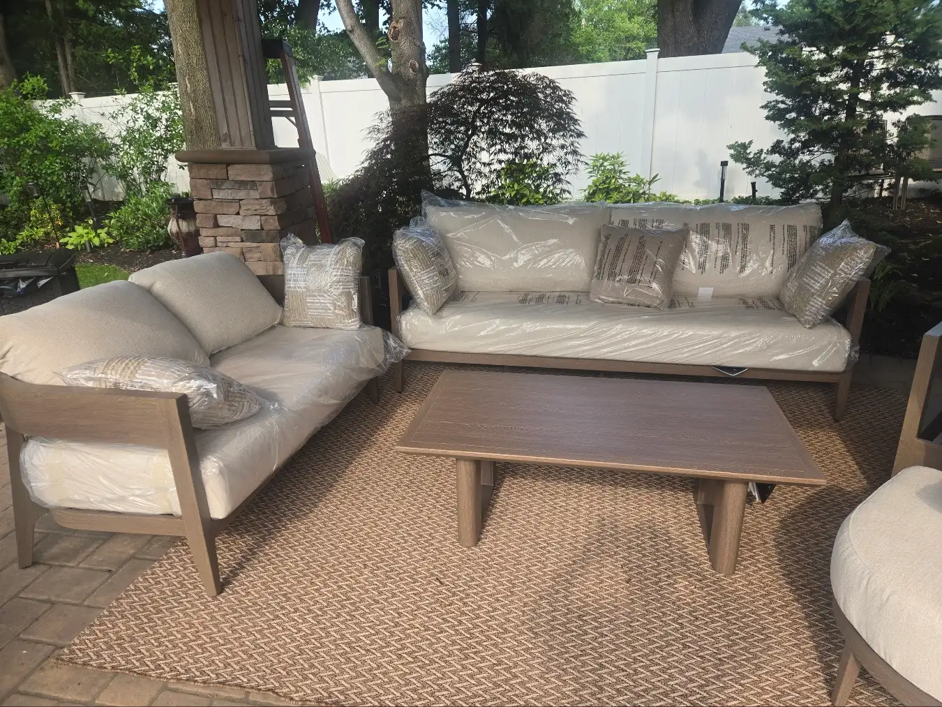 Outdoor couch and love seat with center table on top of an outdoor rug on customer’s patio, delivered by RF Delivery