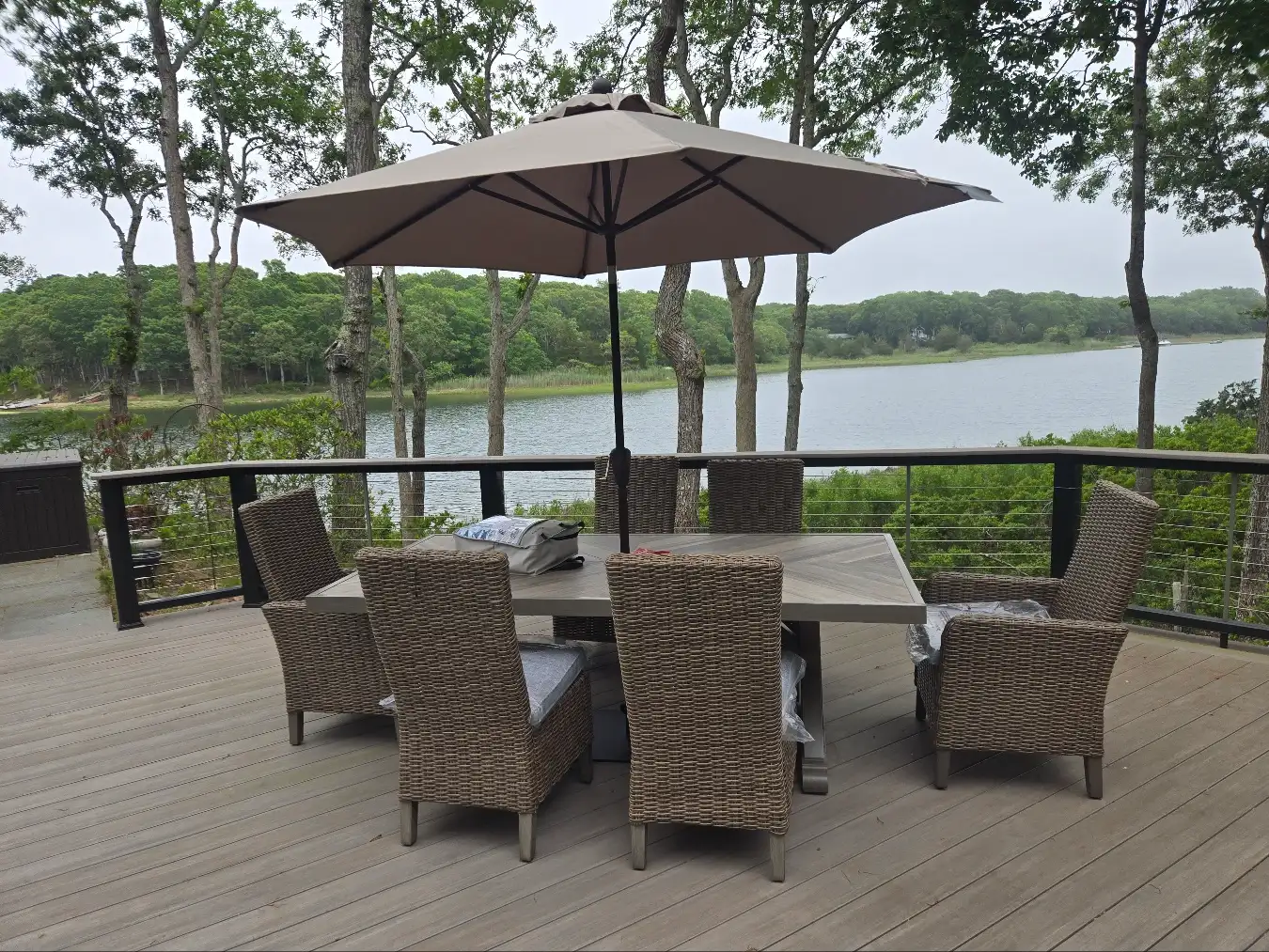 Six patio chairs, table, and umbrella set up on customer’s deck along the river by RF Delivery
